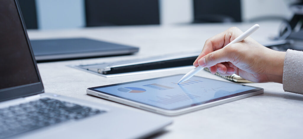 Close-up image of a businessperson reviewing data on a tablet, illustrating how a cybersecurity framework can improve IT assessment outcomes.