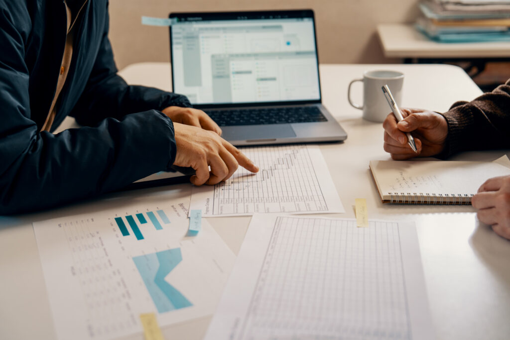 Businesspeople reviewing spreadsheets, representing the need for plan sponsors to address the Roth catch-up requirement