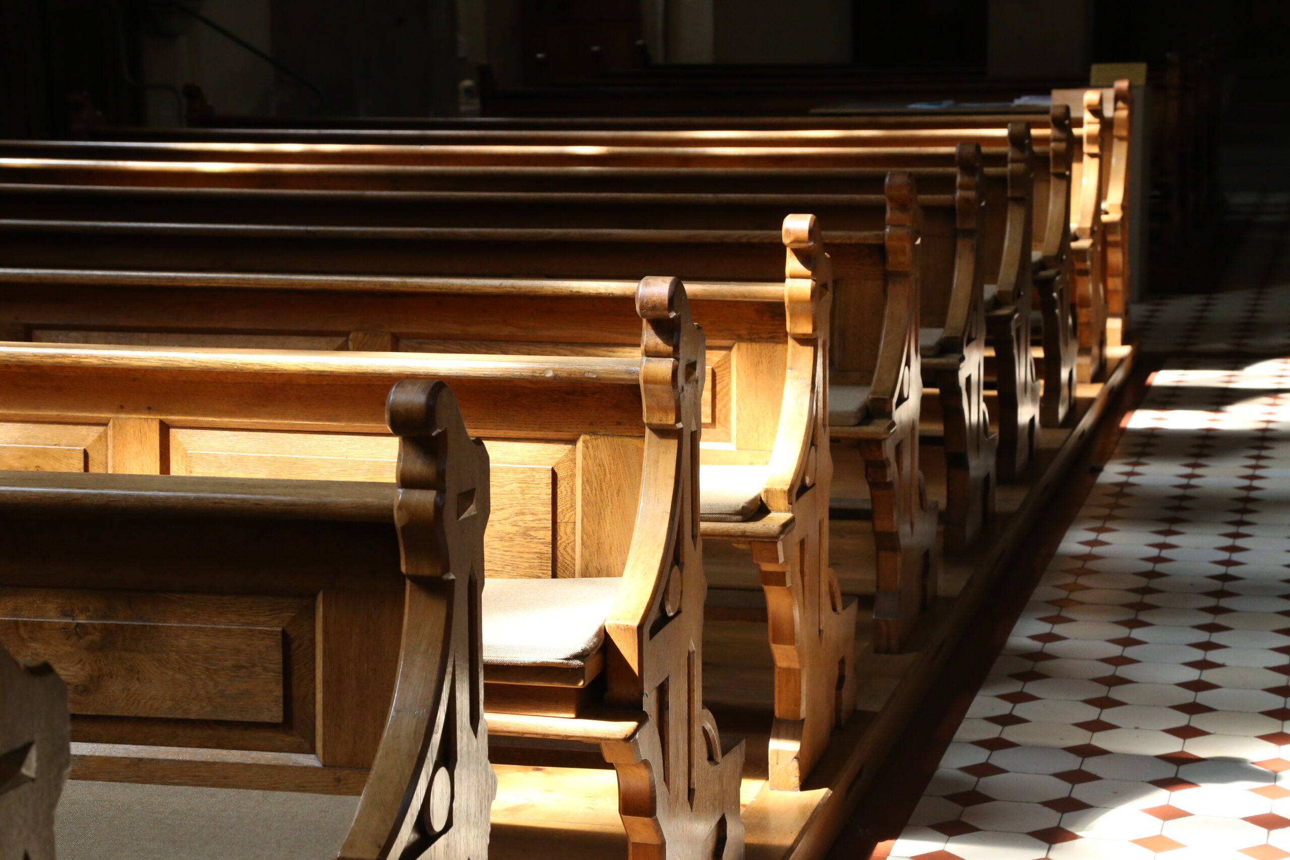 Sunlight on rows of wooden church pews.