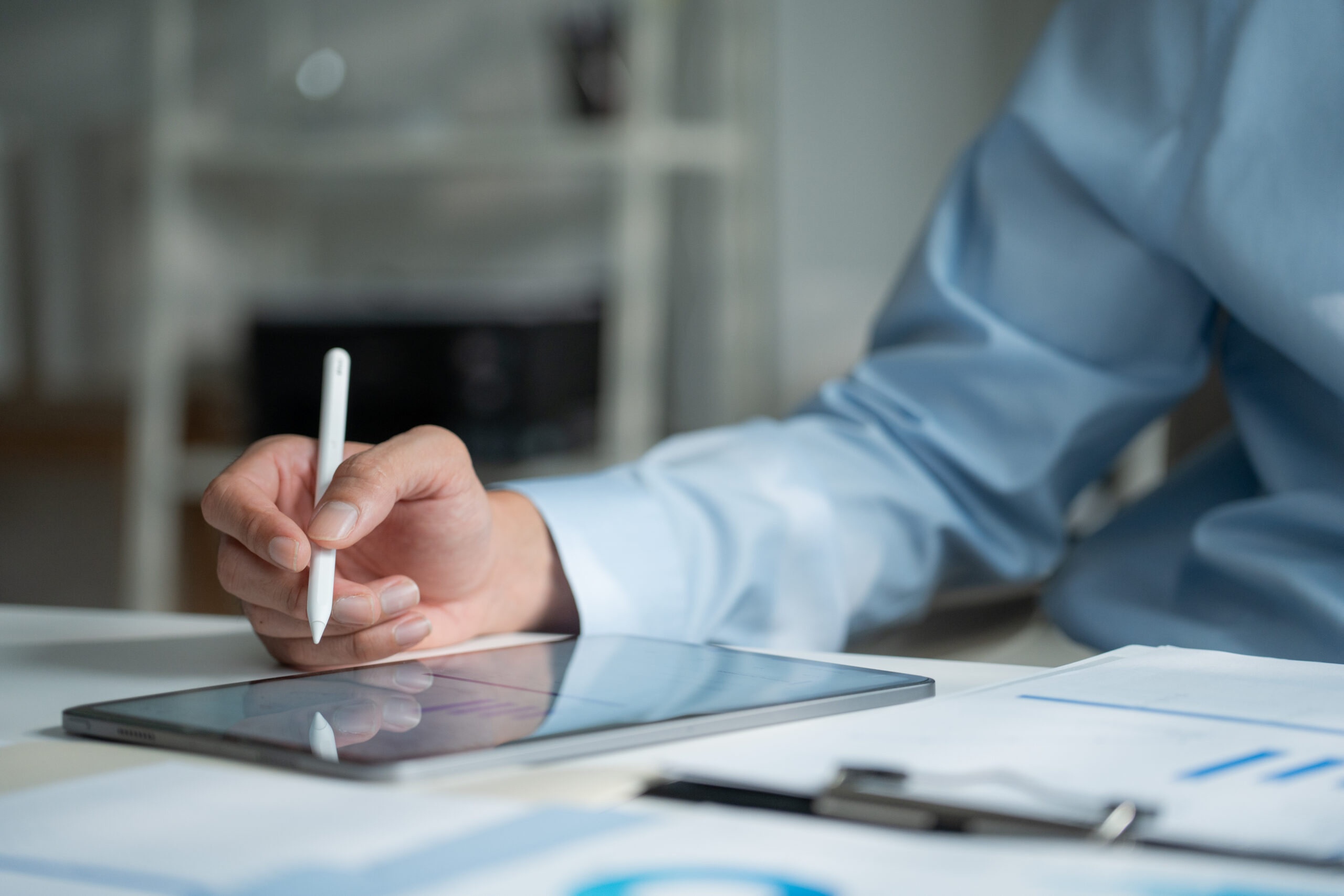 Closeup of an organizational leader’ hand using a stylus pen on a digital tablet screen at a desk, showing review and strategic planning.