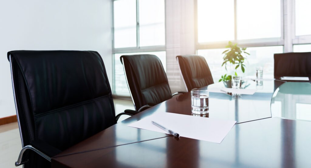 Sunny nonprofit board meeting room with a table, water glasses, and a plant.