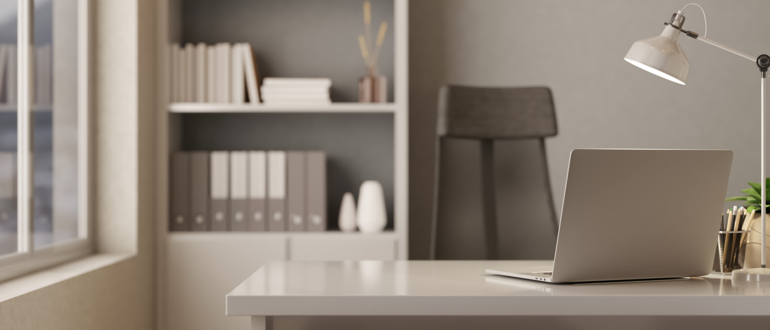 Laptop with lamp and pencils on white table and black chair beside a bookshelf in an office.