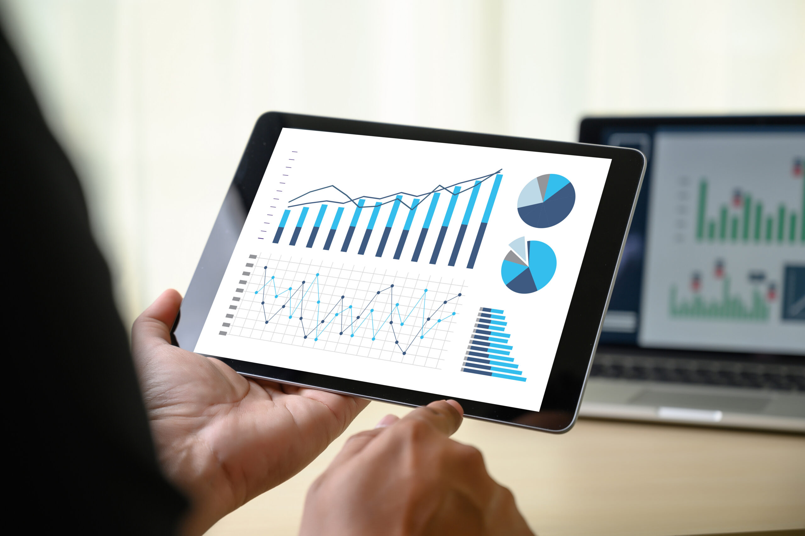 Hand holding a tablet with charts and graphs on the screen, representing accounting tech stack optimization.