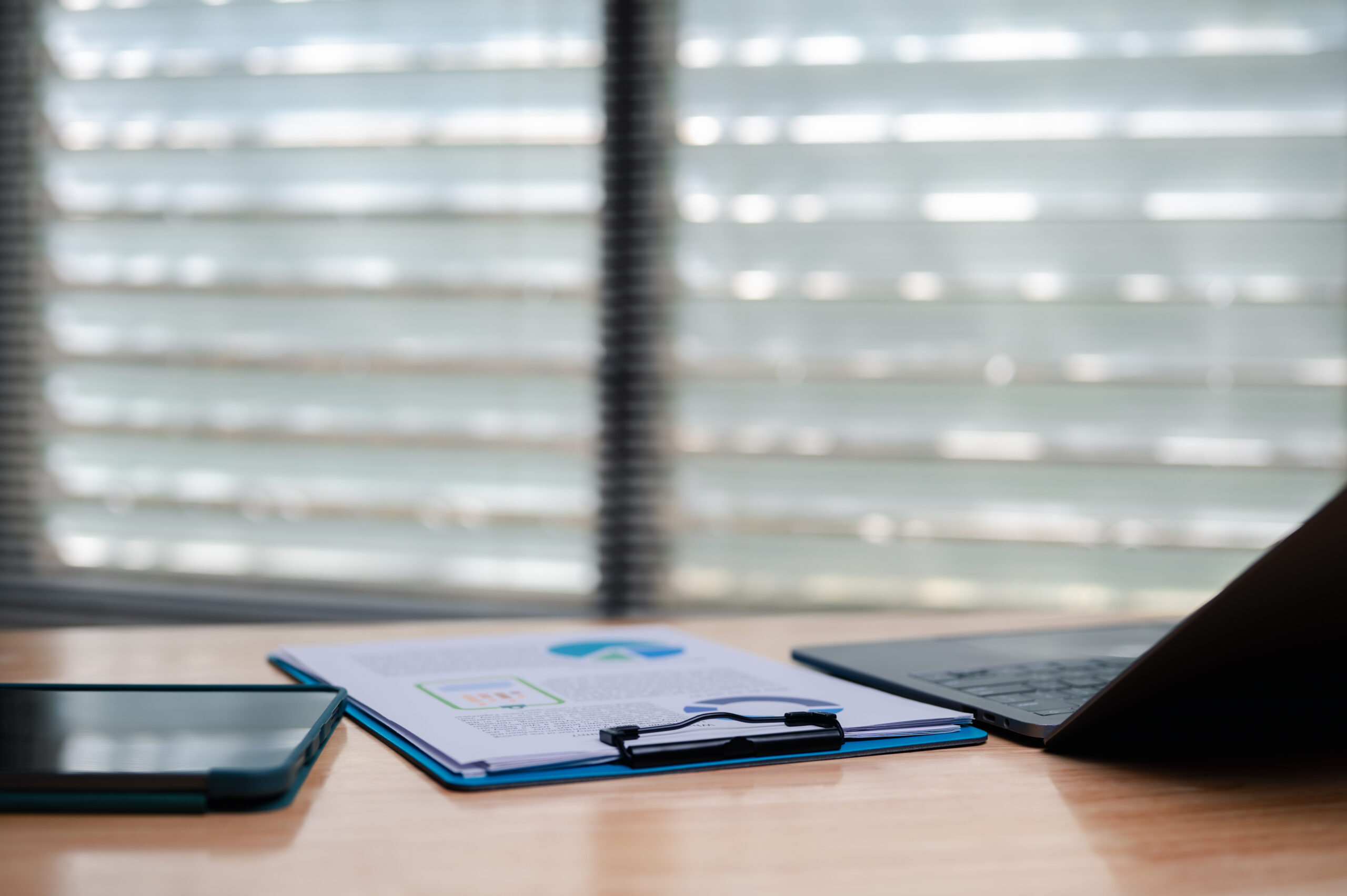 Office scene with paperwork, laptop, and tablet, representing planning for higher education risk assessment.